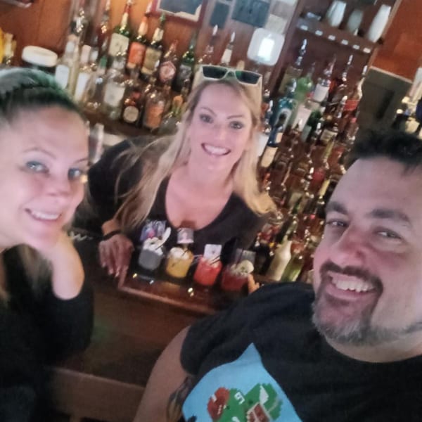 Two smiling women bartenders and a man guest pose for a selfie at Eddington House bar.