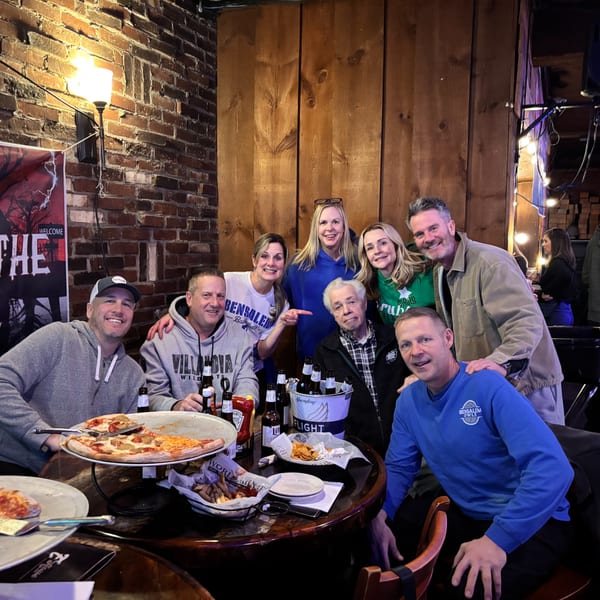 A group of friends enjoying pizza, beer, and fries at Eddington House, an American restaurant.