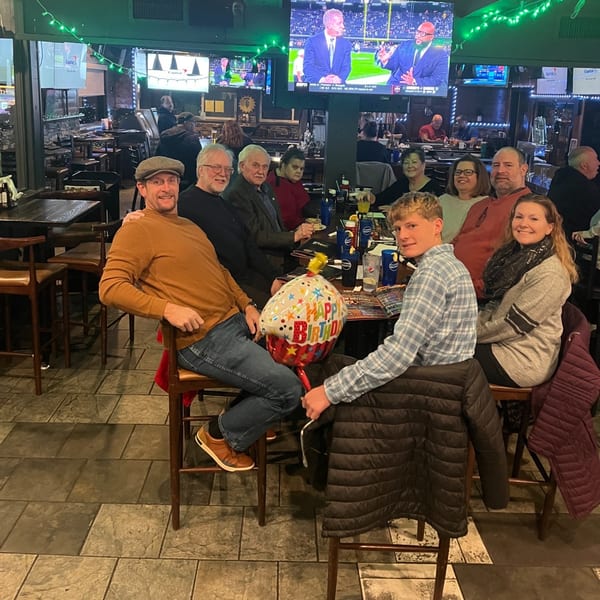A group of people celebrating a birthday at a table in a lively American restaurant.